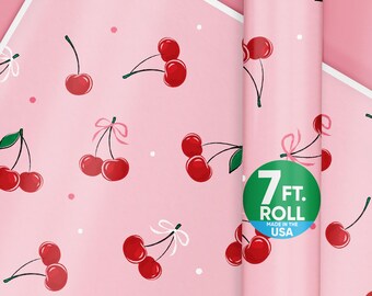 May include: Pink wrapping paper with a repeating pattern of red cherries and white bows. A roll of the same paper is visible, with a green sticker that reads "7 FT. ROLL MADE IN THE USA."