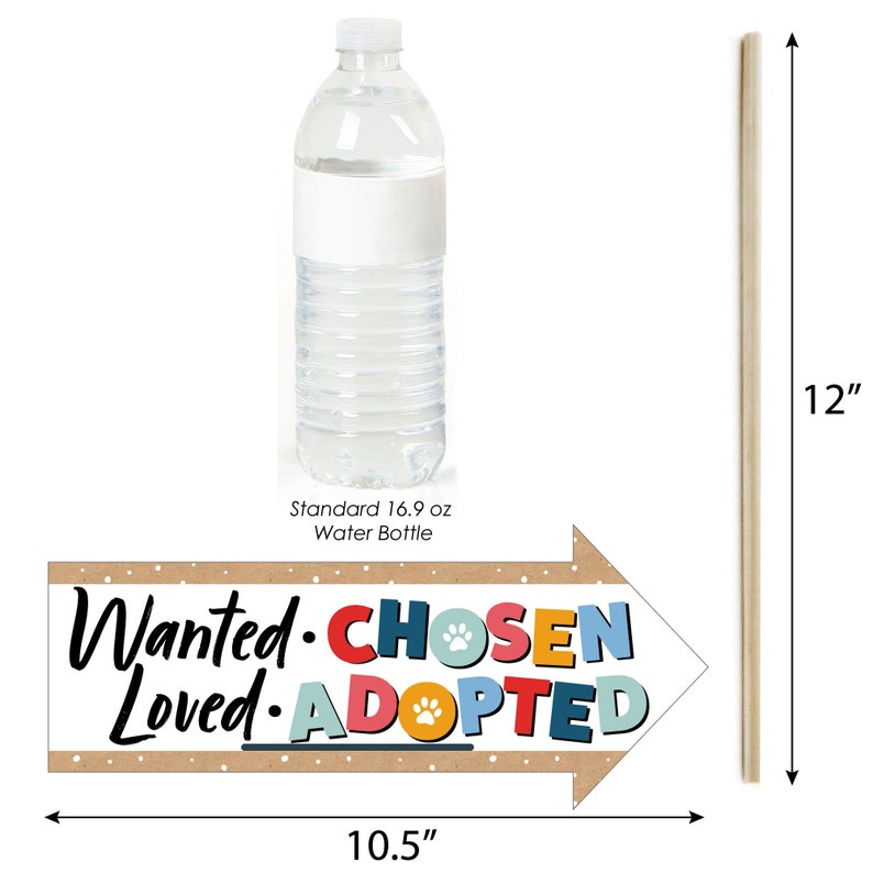 May include: A brown arrow-shaped sign with the text "Wanted. Chosen. Loved. Adopted." in colorful letters with paw prints. The sign is 10.5 inches wide and is propped up with a wooden stick that is 12 inches tall. A standard 16.9 oz water bottle is shown for size comparison.