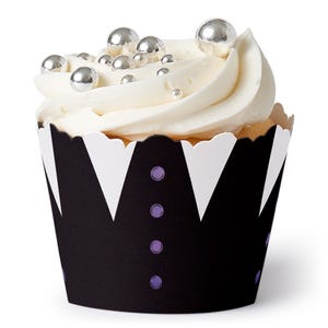 May include: A frosted cupcake with silver ball sprinkles. The cupcake sits in a black and white patterned liner with purple accents. The frosting is white and swirled.