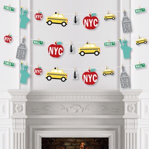 May include: A New York City themed party banner with red apples, yellow taxis, and gray buildings. The banner also includes the text "NYC", "TIMES SQ", and "WALL ST".