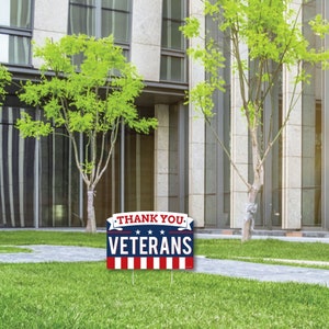 Puede incluir: Un cartel de jard&iacute;n rojo, blanco y azul con el texto "Thank You Veterans" en letras blancas. El cartel tiene un borde rayado rojo, blanco y azul y tres estrellas blancas.