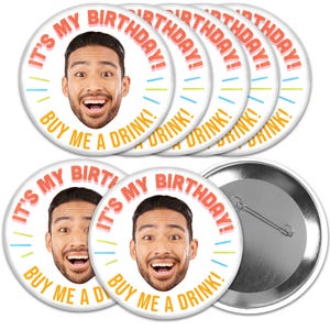 May include: Six round white button badges with a colorful design. The design features a person's face with the text "It's My Birthday! Buy Me A Drink!" in a colorful font.
