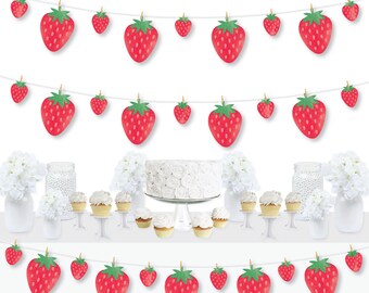 May include: Three strawberry themed party banners with red and green strawberries hanging on white string. The banners are displayed on a table with white cupcakes and a white cake.