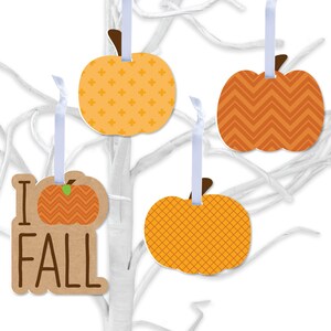 May include: Four fall-themed pumpkin ornaments with different patterns. The ornaments are orange and brown with white string for hanging. One ornament has the text "I Fall" on it.