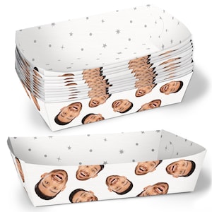 May include: A stack of white paper trays with a repeating pattern of a smiling face and gray stars and dots. The trays are rectangular with slightly curved sides, suitable for serving food.