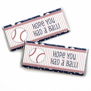 May include: Two rectangular candy bar wrappers featuring a white background with thin red vertical pinstripes, a baseball graphic, and the dark blue text "HOPE YOU HAD A BALL!". The edges are bordered by a red baseball stitch pattern and dark blue.