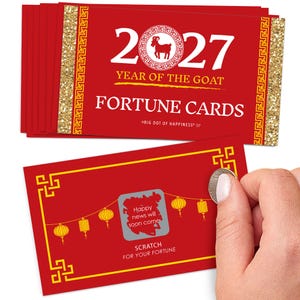 May include: A stack of red rectangular fortune cards for the 2027 Year of the Goat, featuring gold glitter borders and yellow geometric patterns. One card shows a scratch-off area with a lantern design and the text Happy news will soon come.