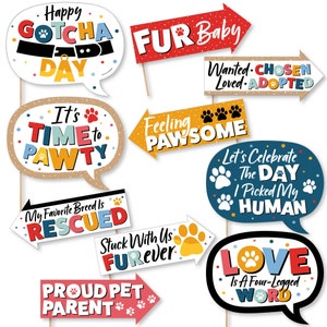 May include: A set of 10 colorful photo booth props with dog-themed sayings. The props are made of cardboard and have sticks attached to the back. The sayings include "Happy Gotcha Day", "Fur Baby", "It's Time to Pawty", "Feeling Pawsome", "My Favorite Breed Is Rescued", "Stuck With Us Furrever", "Proud Pet Parent", "Wanted Chosen Loved Adopted", "Let's Celebrate The Day I Picked My Human", and "Love Is A Four-Legged Word".