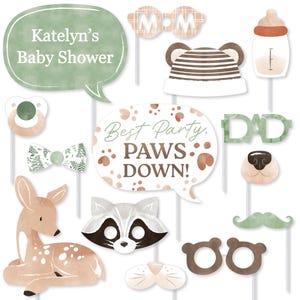 May include: A collection of baby shower photo booth props in shades of brown, green, and white. Includes speech bubbles with text, animal masks, a pacifier, a bow tie, and a baby bottle. The props are designed with a watercolor effect.