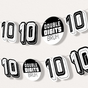 May include: A banner with the number "10" in a bold, black and white design. The banner also includes circular tags with the text "DOUBLE DIGITS BRUH." The banner is strung on a thin, silver string.