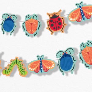 May include: A string of colorful insect-shaped cutouts, including beetles, butterflies, and a caterpillar, strung on a white cord. The insects feature bright colors like blue, orange, red, and green, with a light blue outline. The garland is against a white background.
