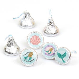 May include: A set of 10 mermaid-themed chocolate kiss stickers. The stickers feature a variety of designs, including a mermaid tail, a seashell, and the text "Let's Be Mermaids".