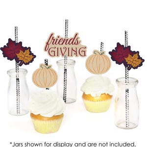 May include: Friendsgiving themed cupcake toppers with a pumpkin, fall leaves, and the text "Friends Giving". The toppers are on black and white striped straws and are displayed on cupcakes and glass jars.