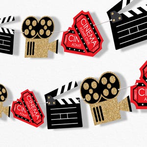 May include: A red and gold glitter movie themed party banner with alternating images of a film clapboard, a movie camera, and tickets that say "Cinema Admit One".