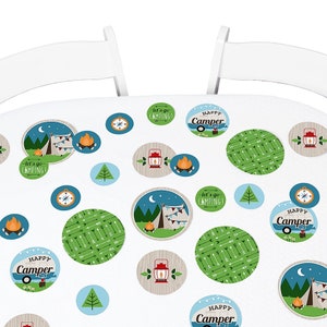 May include: A white tablecloth with a camping theme. The tablecloth is decorated with blue, green, and brown circles featuring images of a campfire, a tent, a compass, a lantern, and arrows. The text "Let's go camping!" and "Happy Camper" is printed on some of the circles.