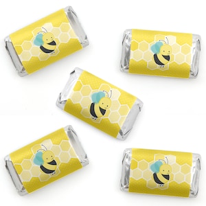May include: Five yellow and white mini chocolate bars wrapped in silver foil with a bee and honeycomb design. The bee is yellow with black stripes and blue wings.