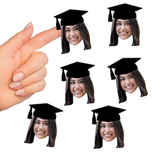 May include: Six black graduation caps with a tassel on each. Each cap has a face of a person wearing a graduation cap underneath. The faces are all the same person.