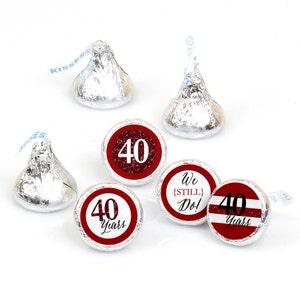 May include: Red and white 40th anniversary chocolate kiss stickers. The stickers feature a red circle with white text and a white circle with red text. The text on the stickers includes "40 Years", "We [Still] Do!" and "40 Years".