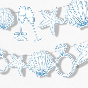 May include: A string of light blue paper cutouts featuring champagne flutes, seashells, starfish, and diamond rings. The decorations are strung on a thin, light-colored string, perfect for a beach-themed party or wedding.