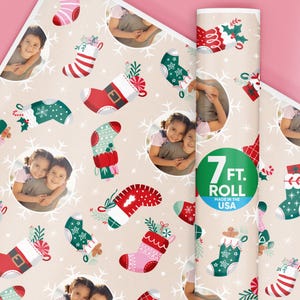 May include: Christmas-themed wrapping paper roll with a repeating pattern of festive stockings in red, green, and pink, with snowflake accents. The roll is 7 ft. and made in the USA.