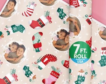 May include: Christmas-themed wrapping paper roll with a repeating pattern of festive stockings in red, green, and pink, with snowflake accents. The roll is 7 ft. and made in the USA.