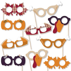 May include: Set of 10 Thanksgiving photo booth props featuring various designs, including a turkey, pumpkin, pie, and a plaid leaf. The props are printed on cardstock and have sticks attached for holding.