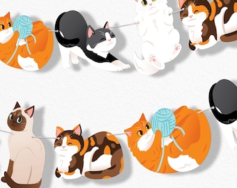 May include: A decorative garland featuring a series of illustrated cats in various poses, including orange cats playing with blue yarn, a stretching black and white cat, a white cat, and calico cats, all strung together on a thin white cord.