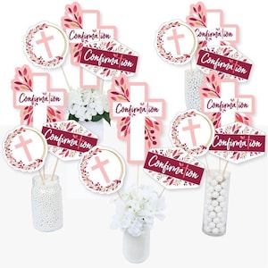 May include: A set of 10 pink and gold confirmation party centerpiece sticks. The sticks feature crosses, wreaths, and the word "Confirmation" in a burgundy script font.
