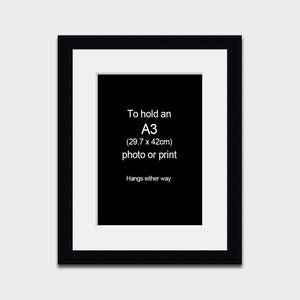 May include: Black picture frame with a white mount, designed to hold an A3 (29.7 x 42cm) photo or print. The text "To hold an A3 (29.7 x 42cm) photo or print. Hangs either way" is printed on the mount.