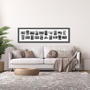 May include: A long, rectangular black picture frame containing a white mat board with twenty individual black and white photographs arranged in a horizontal grid. The frame is mounted on a wall above a white sofa with various throw pillows.