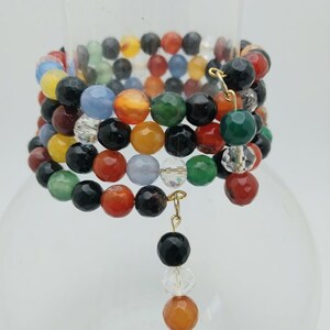 May include: Multi-colored beaded bracelet with a black bead and crystal charm. The bracelet is made of agate, crystal, and other semi-precious stones.