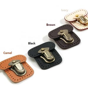 May include: Five leather clasps in different colours: ivory, brown, black, camel, and black. Each clasp has a gold-toned metal latch.