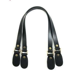 May include: A pair of black leather handbag straps with gold metal hardware. The straps have two loops on each end, allowing for easy attachment to a bag.