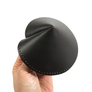 Puede incluir: Un objeto de cuero negro en forma de cono con un borde punteado.