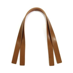 May include: Two brown leather straps with stitching, designed to be used as a handle for a bag.