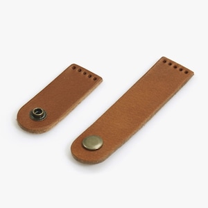 May include: Two brown leather straps with metal button closures. The straps are different sizes.