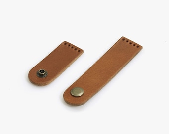 May include: Two brown leather straps with metal button closures. The straps are different sizes.