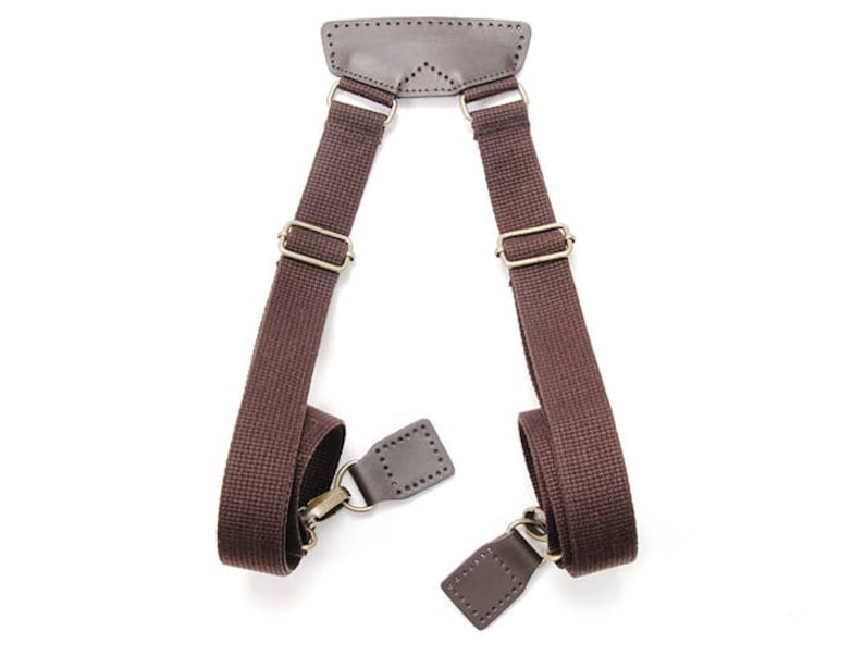 May include: A pair of brown canvas shoulder straps with leather accents and brass hardware. The straps are designed to be attached to a bag or other item.
