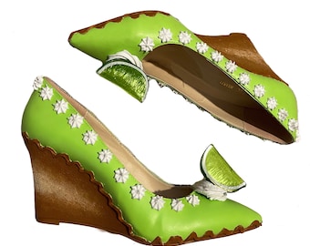 May include: Lime green wedge heels with brown scalloped edges and white star-shaped accents. The shoes feature a pointed toe and a decorative lime slice. The wedge heel is approximately 3 inches high.