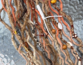 May include: A collection of handmade dreadlocks in various shades of brown, orange, and blonde. The dreads are adorned with wooden beads, shells, and decorative wraps. The texture of the dreadlocks is visible, with a mix of straight and slightly wavy strands.