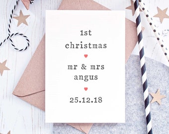 May include: A white card with the text "1st christmas mr & mrs angus 25.12.18" printed in black typewriter font. Two small red hearts are printed above and below the text "mr & mrs angus".