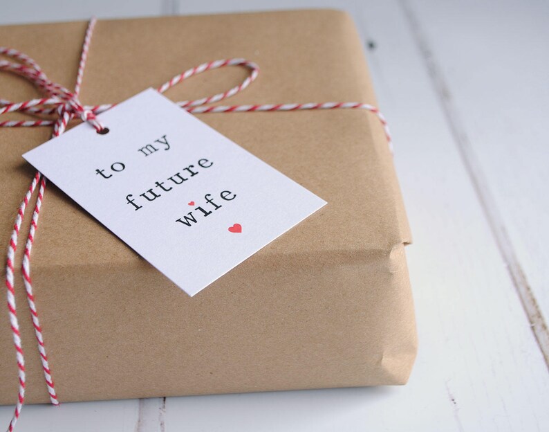May include: A brown paper gift box tied with red and white twine and a white gift tag that says "to my future wife" with a small red heart.