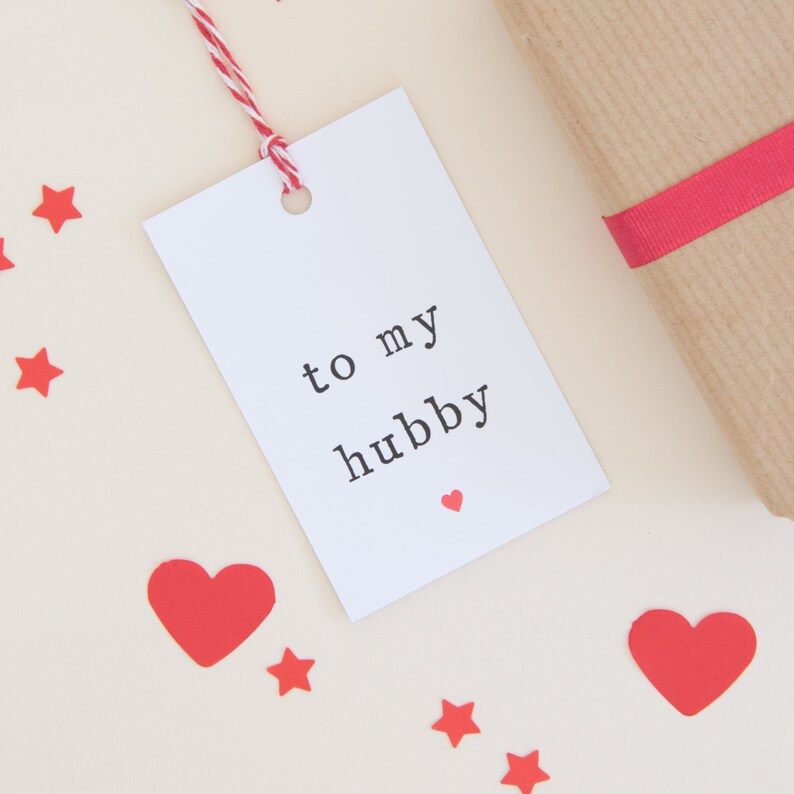 May include: White gift tag with red string, a small red heart, and the text "to my hubby".