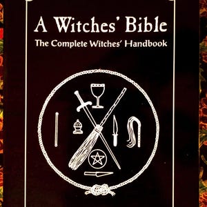 Peut inclure: Un livre noir intitulé "A Witches' Bible" avec du texte blanc et une illustration circulaire de symboles liés à la sorcellerie. La couverture du livre présente une bordure blanche avec des pentagrammes à chaque coin. Les noms des auteurs, Janet et Stewart Farrar, sont en bas.