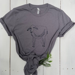 May include: A charcoal gray t-shirt with a black line drawing of a sheep on the front.