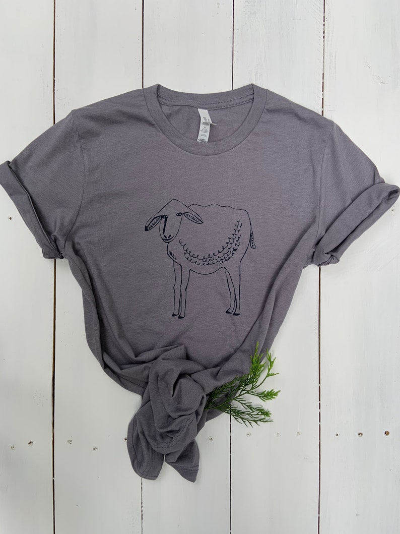 May include: A charcoal gray t-shirt with a black line drawing of a sheep on the front.