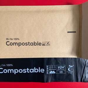 May include: A brown paper envelope with a black plastic liner. Both the envelope and liner have the text "Hi, I'm 100% Compostable" printed on them. The envelope has a seal on the top right corner. The liner has a green leaf logo with the text "OK compost HOME" and "TUV AUSTRIA HOME" printed on it.