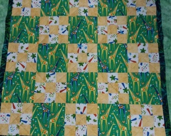 Sweet and unique patchwork quilt with giraffes, palm trees and butterflies in green, yellow & blue with batik borders.