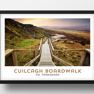 May include: A wooden boardwalk leads up a hill with a view of a valley and a lake in the distance. The text "Cuilcagh Boardwalk Co. Fermanagh" is at the bottom of the image.