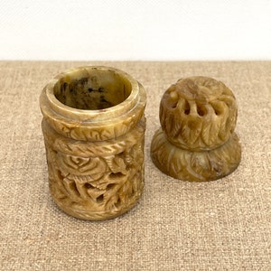 Puede incluir: Una peque&ntilde;a caja de piedra beige, tallada con intrincados detalles, con tapa. La caja est&aacute; decorada con motivos florales y de hojas.